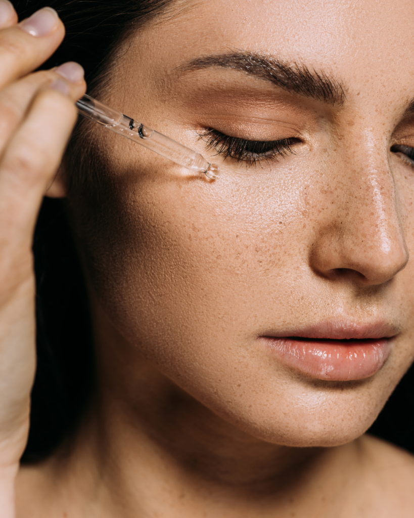 Frascos de sérum con niacinamida y ácido hialurónico junto a un rostro con piel hidratada y protegida.