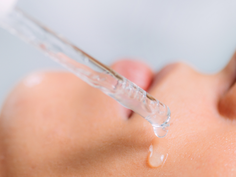 Frasco de sérum con niacinamida junto a un rostro con piel uniforme y luminosa tras su aplicación.