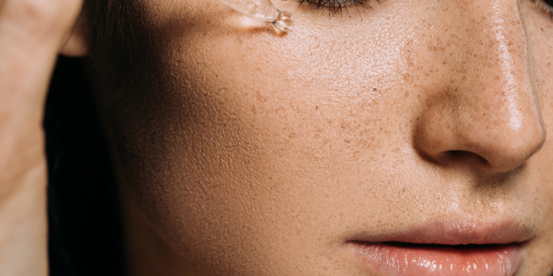 Frascos de sérum con niacinamida y ácido hialurónico junto a un rostro con piel hidratada y protegida.